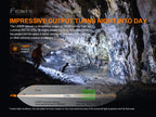 Person exploring a cave with a flashlight, highlighting the light output of a Fenix flashlight.